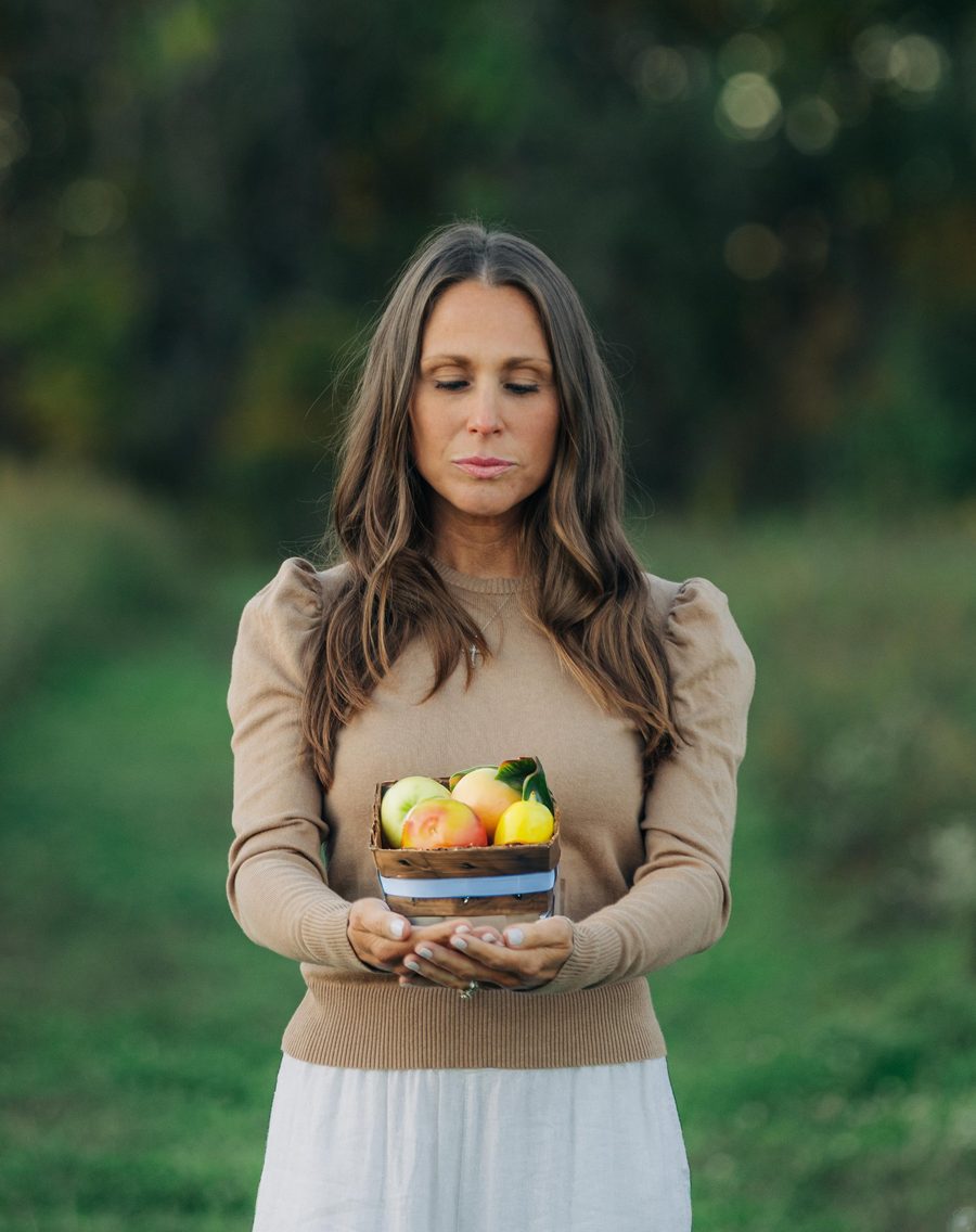Alison holding a small basket of fresh fruit outdoors